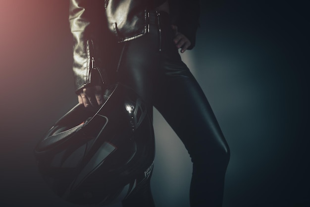 Woman stands holding helmet from motorcycle