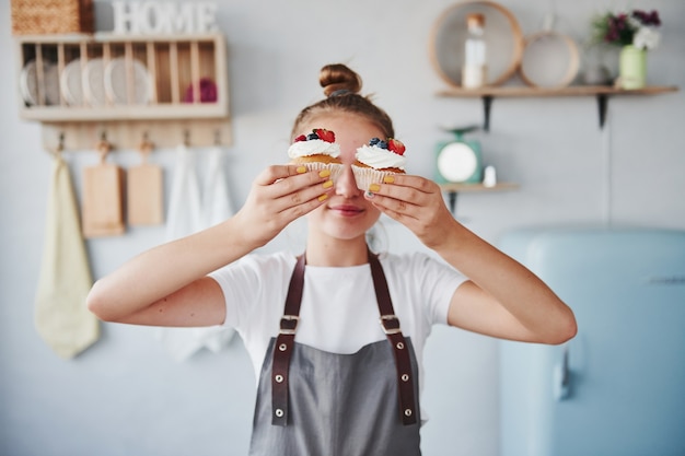 Woman stands indoors in the kitchen with homemade pie.