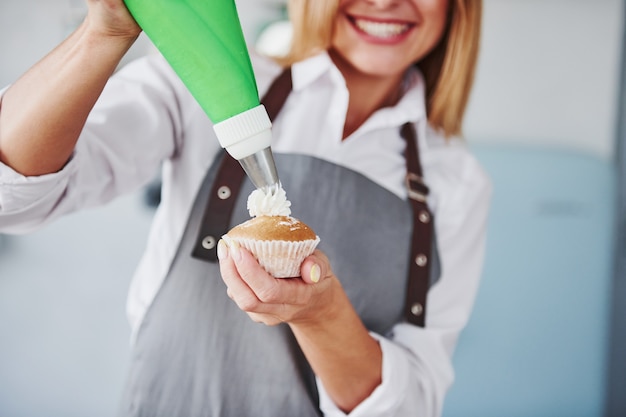 Woman stands indoors in the kitchen with homemade pie.