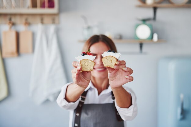 Woman stands indoors in the kitchen with homemade pie.