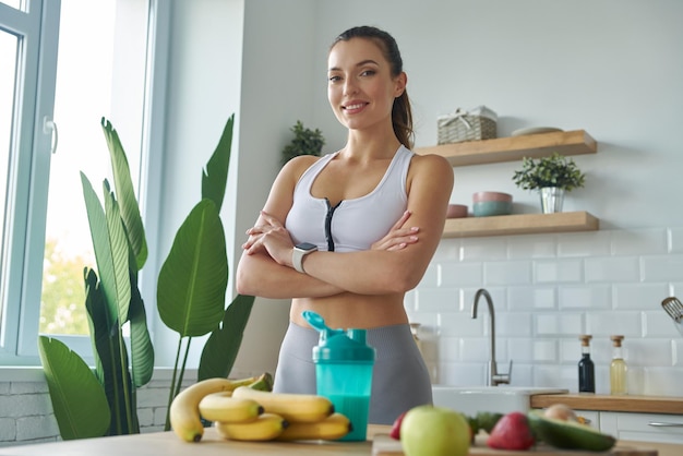 a woman stands in a kitchen with bananas and fruits