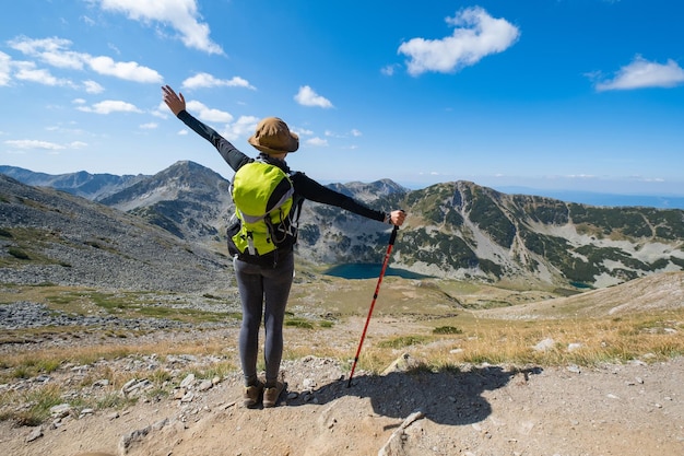 a woman stands on a mountain with her arms outstretched