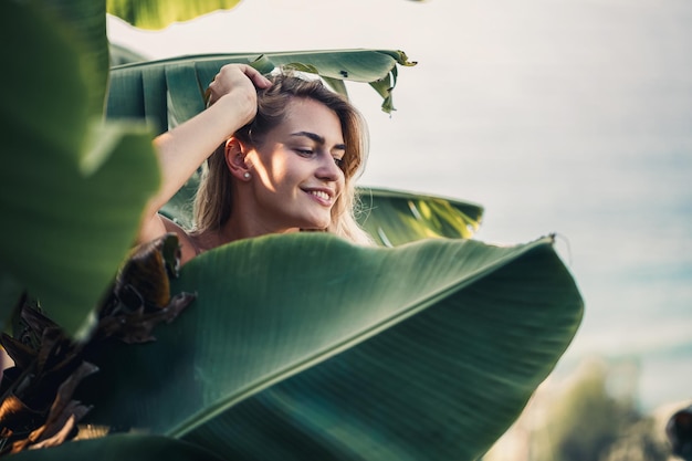 A woman stands near green banana leaves on the island Tropical trees