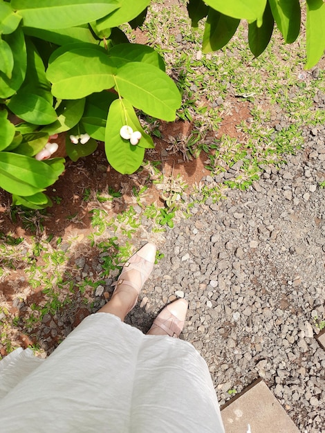 A woman stands on a path with her shoes on.