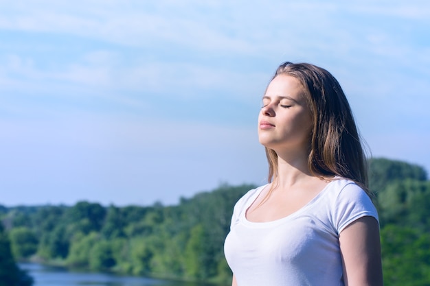 A woman stands with her eyes closed enjoying the sun's rays