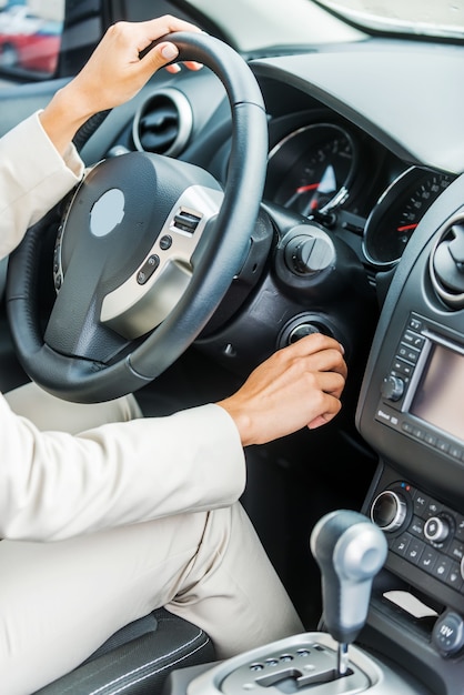 Woman starting a car. Close-up of woman in formalwear starting a car