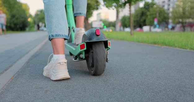 Woman starting a ride on electric scooter Legs on an electric scooter Electric scooter close up Renewable energy transport