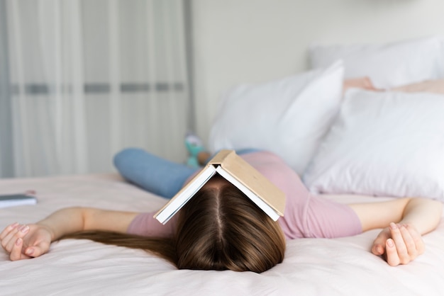 Woman staying in bed with a book covering her face