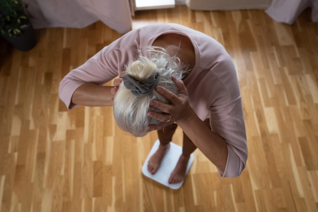 Woman stepping on floor scales closeup Weight control