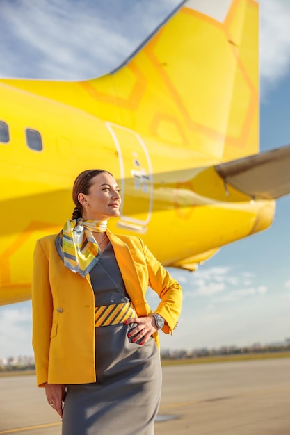 Woman stewardess wearing aviation air hostess uniform while standing outdoors at airport