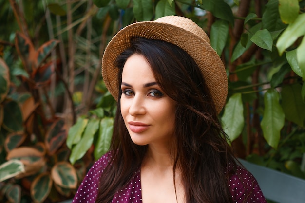 Woman in a straw hat sitting on a bench in the park