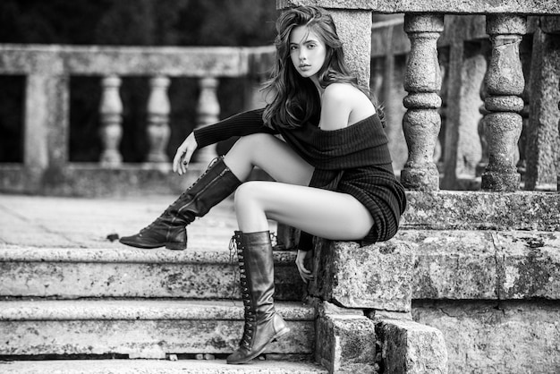 Woman street style fashion model sit on the retro vintage stairs in the old city street casual every