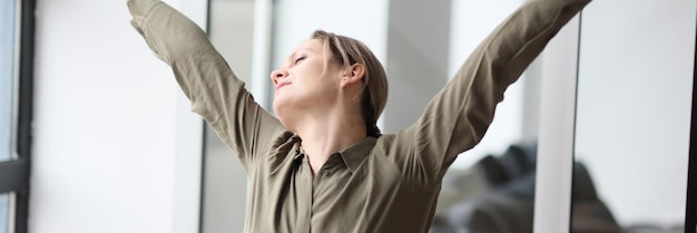 Woman stretches arms and back after monotonous work in office female employee in blouse takes