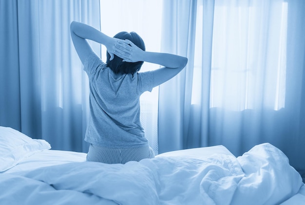 Woman stretching in bed after wake up with copy space