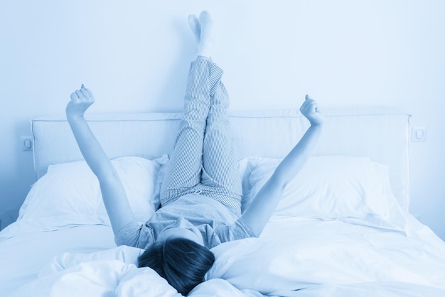 Woman stretching in bed with legs raised up high in bedroom