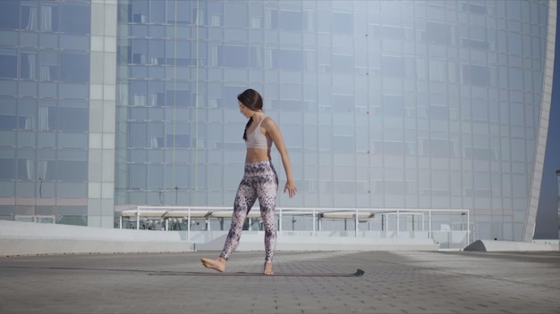 Woman stretching body on city street Athletic girl doing yoga in city