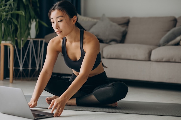 Woman stretching on yoga mat at home