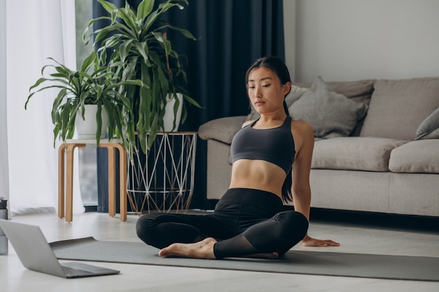 Woman stretching on yoga mat at home