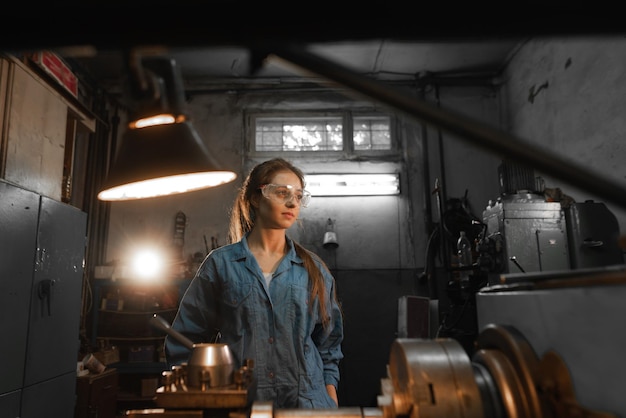 Woman student works on an automatic lathe CNC industrial workshop Concept vocational education turner