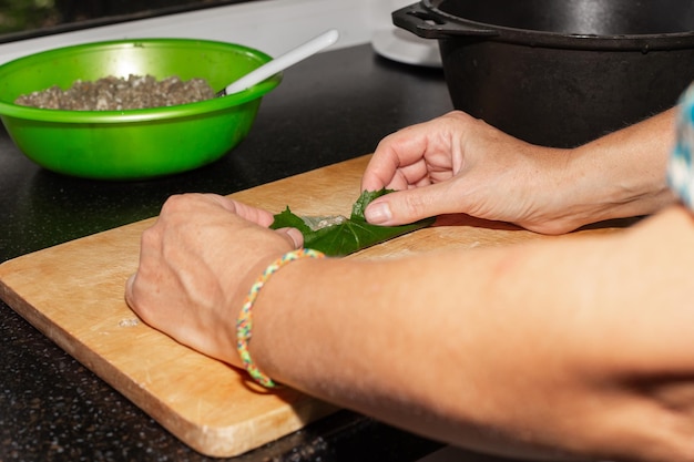 A woman stuffs grape leaves with meat Cooking Caucasian dish dolma