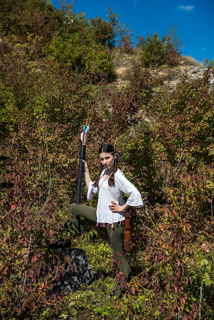 Woman in style as native peoples of America with a bow and arrow