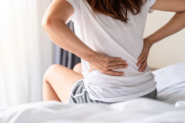 Woman suffering from back ache on the bed, healthcare and problem concept