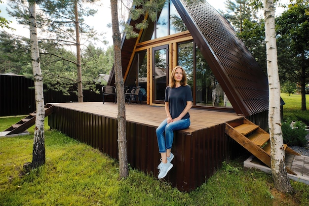 Woman in a summer house sitting on terrace and enjoys beautiful view and fresh air