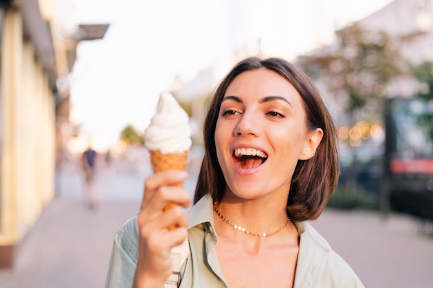 Woman at summer sunset time having ice cream cone at city street