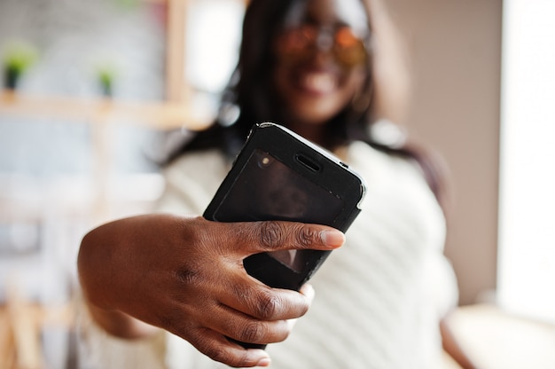 Woman in sunglasses posed at modern cafe and making selfie on phone