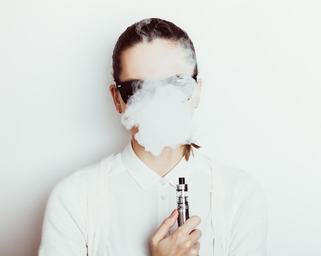 Woman in sunglasses smokes an e-cigarette