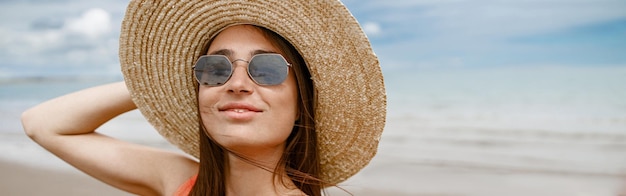 Woman in sunglasses standing on beach near sea during vacation and making selfie