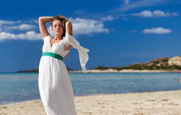 Woman on sunny sea beach in white fluttering dress elafonissi grece