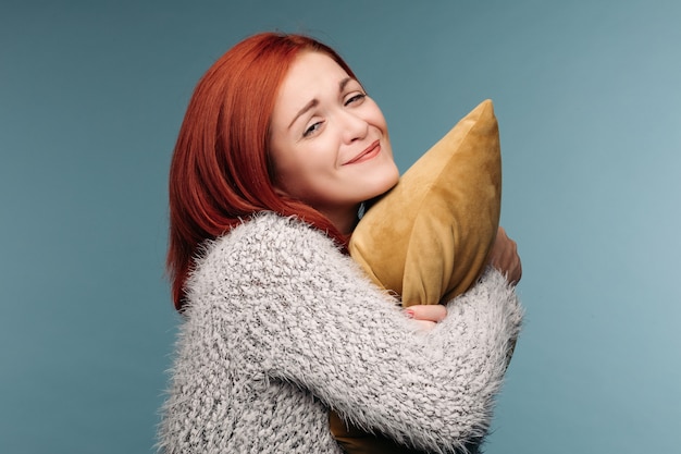 woman in a sweater hugging a pillow.