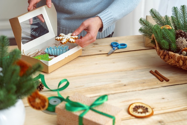 Woman in a sweater puts cookies iced gingerbread