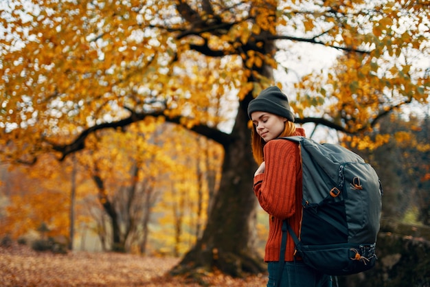 Photo woman in a sweater walks in the park in autumn nature landscape fresh air model backpack