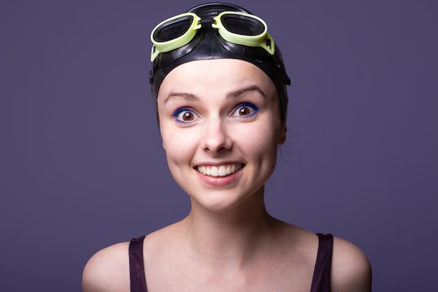 woman swimmer in a swimming cap glasses and a swimsuit gray background