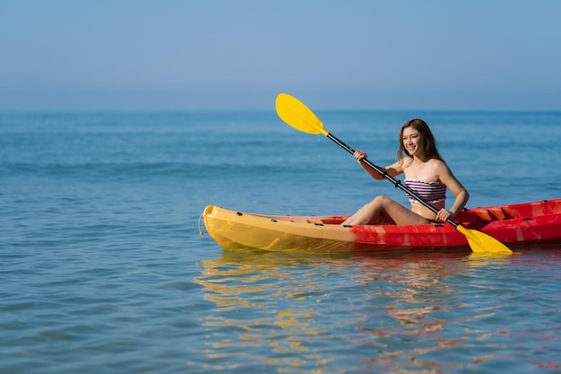 Woman in swimsuit paddling a kayak boat in the sea