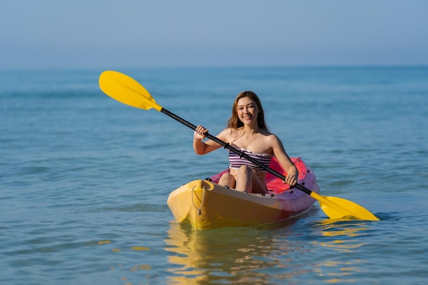 Woman in swimsuit paddling a kayak boat in the sea