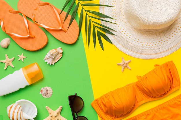 Photo woman swimwear and beach accessories flat lay top view on colored background summer travel concept bikini swimsuit straw hat and seasheels copy space top view