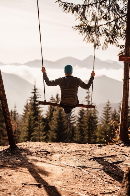 Woman swinging on swing in sunny winter dayin the ferest Wooden swing with swinging free happy woman outdoors Healthy lifestyle vacation Zazriva slovakia