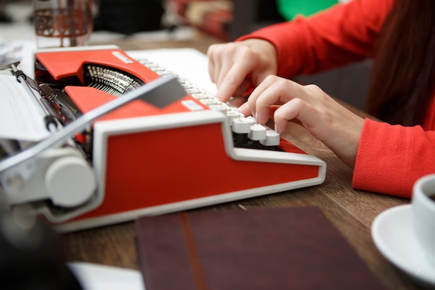 Woman at table typing on typewriter