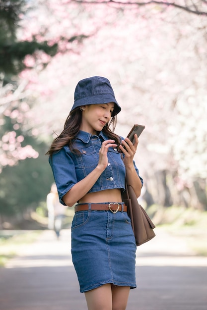 Woman take selfie with cherry blossoms or sakura flower blooming in the park