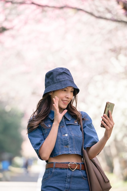 Woman take selfie with cherry blossoms or sakura flower blooming in the park