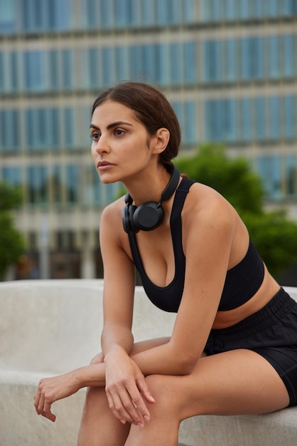  woman takes break after physical exercises cardio training dressed in tracksuit thinks about future sport career looks into distance feels good from well done outdoor workout