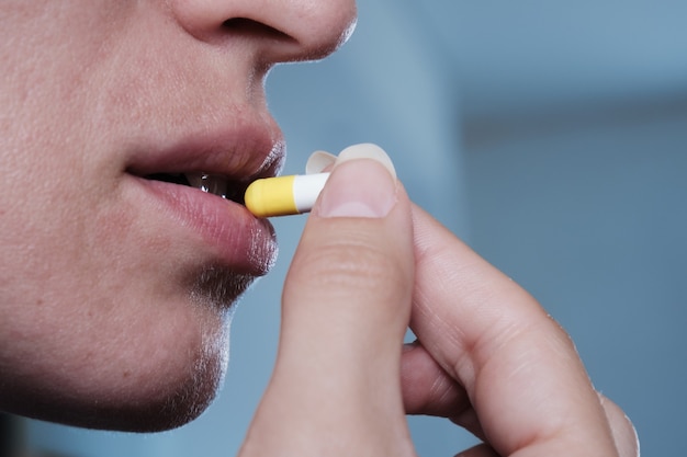 A woman takes a capsule of medicine. Consumption of the drug. Treatment of the disease.