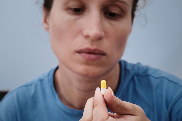 A woman takes a capsule of medicine. Consumption of the drug. Treatment of the disease.