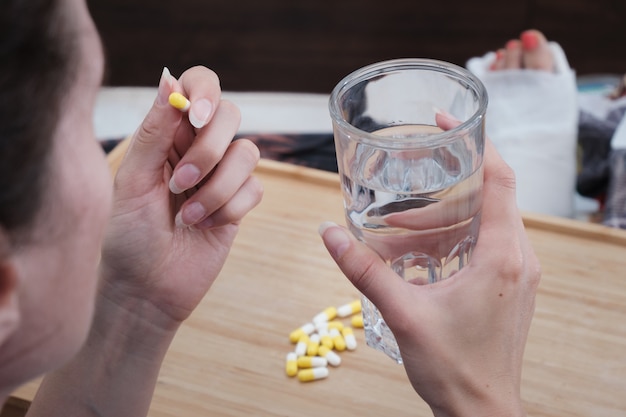 A woman takes a capsule of medicine. Consumption of the drug. Treatment of the disease.