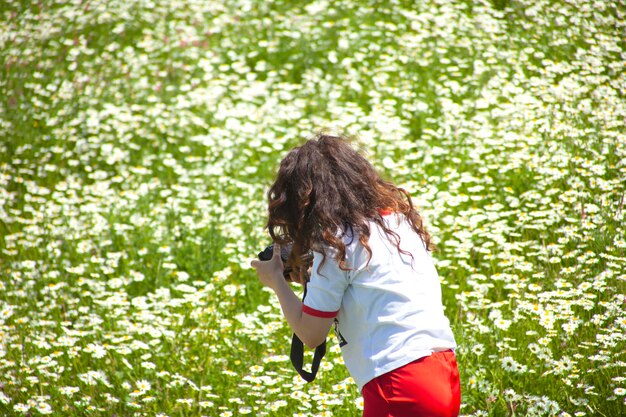 Woman takes a photo in a chamomile field