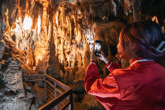 Photo a woman takes a photo inside a captivating cave using her smartphone to capture the ancient formations and scenic beauty