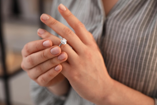 Woman taking off wedding ring indoors closeup Divorce concept